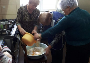 Seniorki z Klubu "Senior+" przygotowują ciasto na pączki.